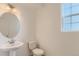 Powder room features a pedestal sink, a round mirror, and a window at 771 Sunflower Dr, Brighton, CO 80601