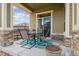 Covered patio with stone accents, outdoor seating, and sliding glass door at 22965 E Bailey Cir, Aurora, CO 80016