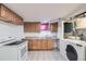 Kitchen with light wood cabinets, white appliances and tile flooring, including washer and dryer at 8471 Rainbow Ave, Denver, CO 80229