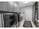 Modern laundry room with front load washer and dryer, cabinets, and unique wallpaper at 13633 Mariposa St, Broomfield, CO 80023