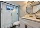 Modern bathroom featuring sleek glass-enclosed shower, white subway tile and round mirror at 8340 W 70Th Ave, Arvada, CO 80004