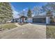 Landscaped ranch-style home with a gray roof, black garage door, and walkway to the red front door at 8340 W 70Th Ave, Arvada, CO 80004