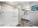 A modern bathroom featuring a glass shower with a built-in seat and neutral wall and floor tiling at 27130 E Maple Ave, Aurora, CO 80018