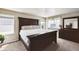 Primary bedroom with a large dark wood bed frame, neutral walls, carpet flooring, and bright natural light at 27130 E Maple Ave, Aurora, CO 80018