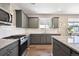 Granite countertops and stainless appliances are featured in this well-lit kitchen with grey-green cabinets at 27130 E Maple Ave, Aurora, CO 80018