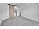 Bright bedroom featuring grey carpet and a barn door leading to the bathroom at 12644 W Virginia Ave, Lakewood, CO 80228