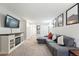 Living room featuring a gray sectional sofa, mounted TV, and functional storage with artwork decorating the walls at 1155 N Ash St # 102, Denver, CO 80220