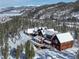 A beautiful aerial view shows the snow-covered home surrounded by a forest and mountains in the background at 300 Gold Hill Rd, Breckenridge, CO 80424