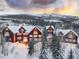 A stunning image of the property with snow-covered roof, large windows, and mountains in the background during sunset at 300 Gold Hill Rd, Breckenridge, CO 80424