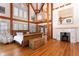 Spacious main bedroom with a fireplace, exposed wooden beams, hardwood floors, and a small second-story balcony at 300 Gold Hill Rd, Breckenridge, CO 80424