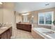 Bathroom showcasing a soaking tub, double vanity, and neutral tile flooring at 9669 E Prentice Cir, Greenwood Village, CO 80111