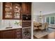 Wet bar features a wine fridge, stainless steel sink, marble countertops, and custom glass front cabinets at 9669 E Prentice Cir, Greenwood Village, CO 80111