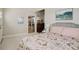 Comfortable bedroom featuring a floral patterned quilt, neutral walls, and a glimpse into the adjacent kitchen at 19810 County Road 1, Berthoud, CO 80513