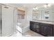 Well-lit bathroom boasts dual vanity, tub, and shower with sleek glass door and subway tile at 6214 Long Branch Dr, Parker, CO 80134