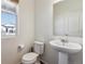 Powder room with white fixtures, pedestal sink, and natural light from a window at 6214 Long Branch Dr, Parker, CO 80134