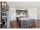 Modern kitchen featuring dark cabinetry, stainless steel appliances, and a large center island with countertop sink at 6214 Long Branch Dr, Parker, CO 80134