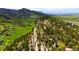 An aerial view shows a mountainous landscape with scattered homes among the trees and open fields at 8932 Eastridge Rd, Golden, CO 80403