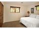A simply decorated bedroom with a white comforter and natural light coming from windows overlooking nature at 8932 Eastridge Rd, Golden, CO 80403