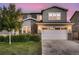 Home exterior featuring a wide two-car garage, stone details, and a well-maintained lawn at 6894 E 133Rd Pl, Thornton, CO 80602