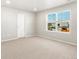 This bedroom features neutral paint and carpet, a window, and a door at 259 E 4Th St, Berthoud, CO 80513