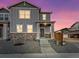 Two-story home boasts stone accents, neutral gray siding, and a welcoming front porch, set against a colorful twilight sky at 259 E 4Th St, Berthoud, CO 80513