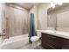 Modern bathroom features a bathtub with shower and modern vanity with dark wood finish at 1813 W 67Th Ave, Denver, CO 80221