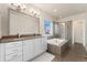Bathroom featuring double vanity sinks, a soaking tub, and a glass-enclosed shower at 1813 W 67Th Ave, Denver, CO 80221