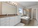 Well-lit bathroom featuring a double vanity, soaking tub, and tiled shower with frameless glass door at 1813 W 67Th Ave, Denver, CO 80221