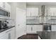 Modern kitchen featuring stainless steel appliances, sleek white cabinets, stone countertops, and modern backsplash at 1813 W 67Th Ave, Denver, CO 80221