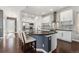 Modern kitchen with white cabinets, an island with seating, stainless steel appliances, and dark hardwood floors at 1813 W 67Th Ave, Denver, CO 80221