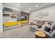 Finished basement living room with gray sectional sofa, wet bar, tv, and gray tufted ottoman at 1813 W 67Th Ave, Denver, CO 80221