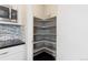 Walk-in pantry with shelving for organized storage, adjacent to stainless microwave at 1813 W 67Th Ave, Denver, CO 80221