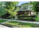 Lovely two-story home boasts a manicured lawn, mature trees, and wrought iron fencing at 325 S High St, Denver, CO 80209