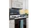 Close up of the kitchen's gas range with white cabinetry and decorative backsplash at 2210 E Mississippi Ave # 3, Denver, CO 80210