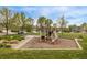 Community playground with slide and play structure surrounded by lush green grass and mature trees on a sunny day at 14713 Josephine St, Thornton, CO 80602