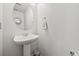 A clean bathroom features a pedestal sink, round mirror, and a towel hook, for a modern design at 4056 Perth St, Denver, CO 80249