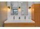 Bathroom vanity featuring dual sinks, modern lighting fixtures and wood cabinets, offering functionality and style at 6260 Lamar St, Arvada, CO 80003