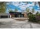 Contemporary home with a dark exterior, stone chimney, and an attached two-car garage at 6260 Lamar St, Arvada, CO 80003