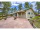 Backyard patio featuring stone pavers, a gazebo, garden beds, and mature pine trees at 26732 Main St, Conifer, CO 80433