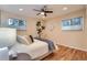 Cozy bedroom featuring hardwood floors, a ceiling fan, and large windows for natural light at 26732 Main St, Conifer, CO 80433