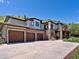 Large driveway leading to a three car garage with stone accents and lush landscaping at 6405 Warriors Run, Littleton, CO 80125