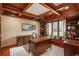 Home office featuring custom woodwork, a coffered ceiling, built-in bookshelves, and a bright window at 7965 S Eudora Cir, Centennial, CO 80122