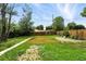 Fenced backyard featuring a grassy area, surrounding trees, and partial view of neighboring houses at 1941 Alton St, Aurora, CO 80010