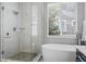 Bright bathroom showcases a soaking tub, glass-enclosed shower, and window with blinds for privacy at 3092 Fox Sedge Pl, Highlands Ranch, CO 80126