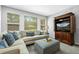 Living room with sofa, large windows, ottoman, and entertainment center at 3092 Fox Sedge Pl, Highlands Ranch, CO 80126
