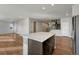 Spacious kitchen island with a sleek countertop, stainless steel appliances, and a view of the staircase at 15902 Stringhalt Way, Parker, CO 80134