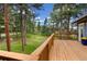 Scenic view from the wooden deck overlooking a lush green lawn, framed by towering trees and a beautiful landscape at 4835 Abo Ln, Monument, CO 80132