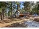 Charming multi-level home featuring a stone chimney, gray wood siding, and a spacious wood deck at 4835 Abo Ln, Monument, CO 80132