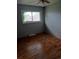 An empty bedroom with hardwood floors, freshly painted walls, a ceiling fan, and a window overlooking the yard at 6027 W 61St Pl, Arvada, CO 80003
