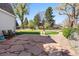 Backyard featuring a stone patio, manicured lawn, trees, and partial fence at 6990 W 9Th Pl, Lakewood, CO 80214